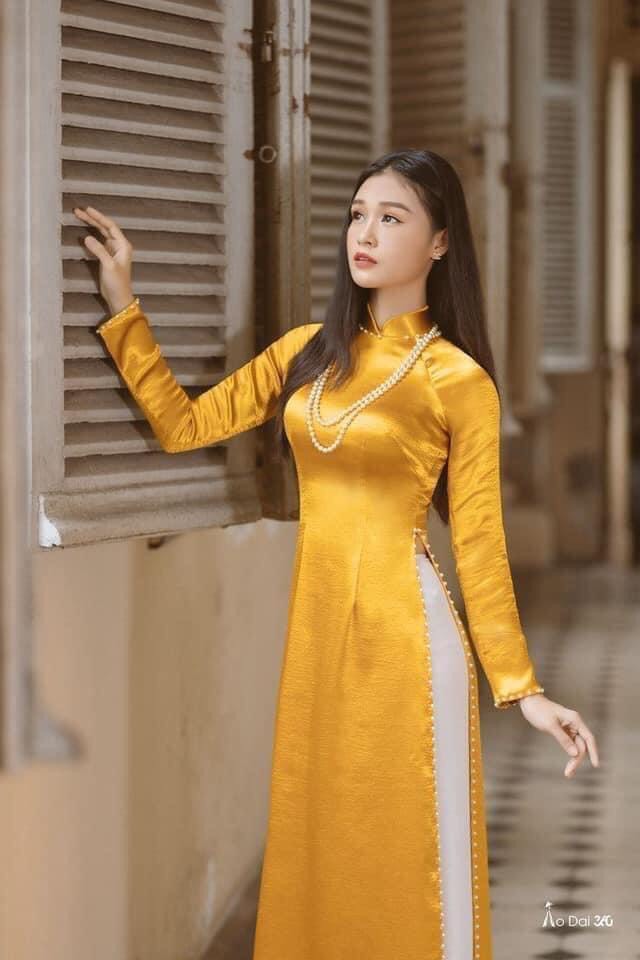 Áo dài vân gỗ màu vàng đồng phối ngọc tôn da