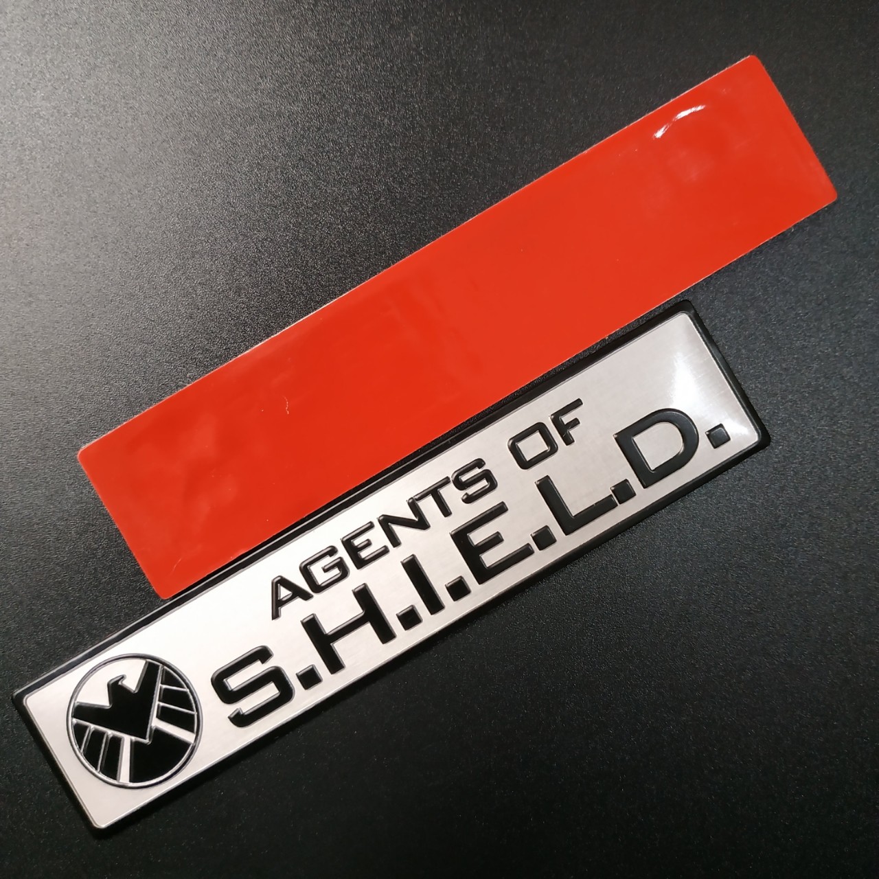 Tem nhôm dán xe SHIELD dài 12x2.6cm nền trắng