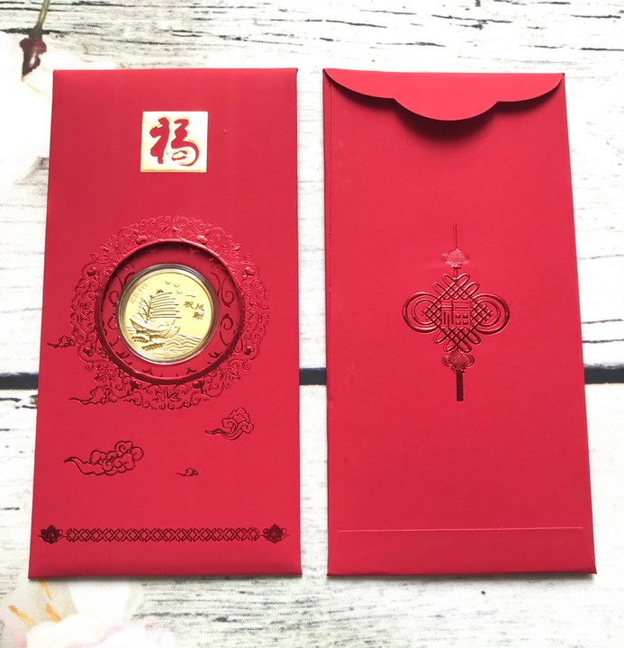 Bao lì xì mạ vàng Thuận Buồm Xuôi Gió, ở giữa có một đồng xu hình chiếc thuyền đang căng buồm ra khơi lộng gió, được ốp nhựa acrylic bên ngoài; Dài 17cm - Ngang 7cm - Cao 0.3cm - SP005082